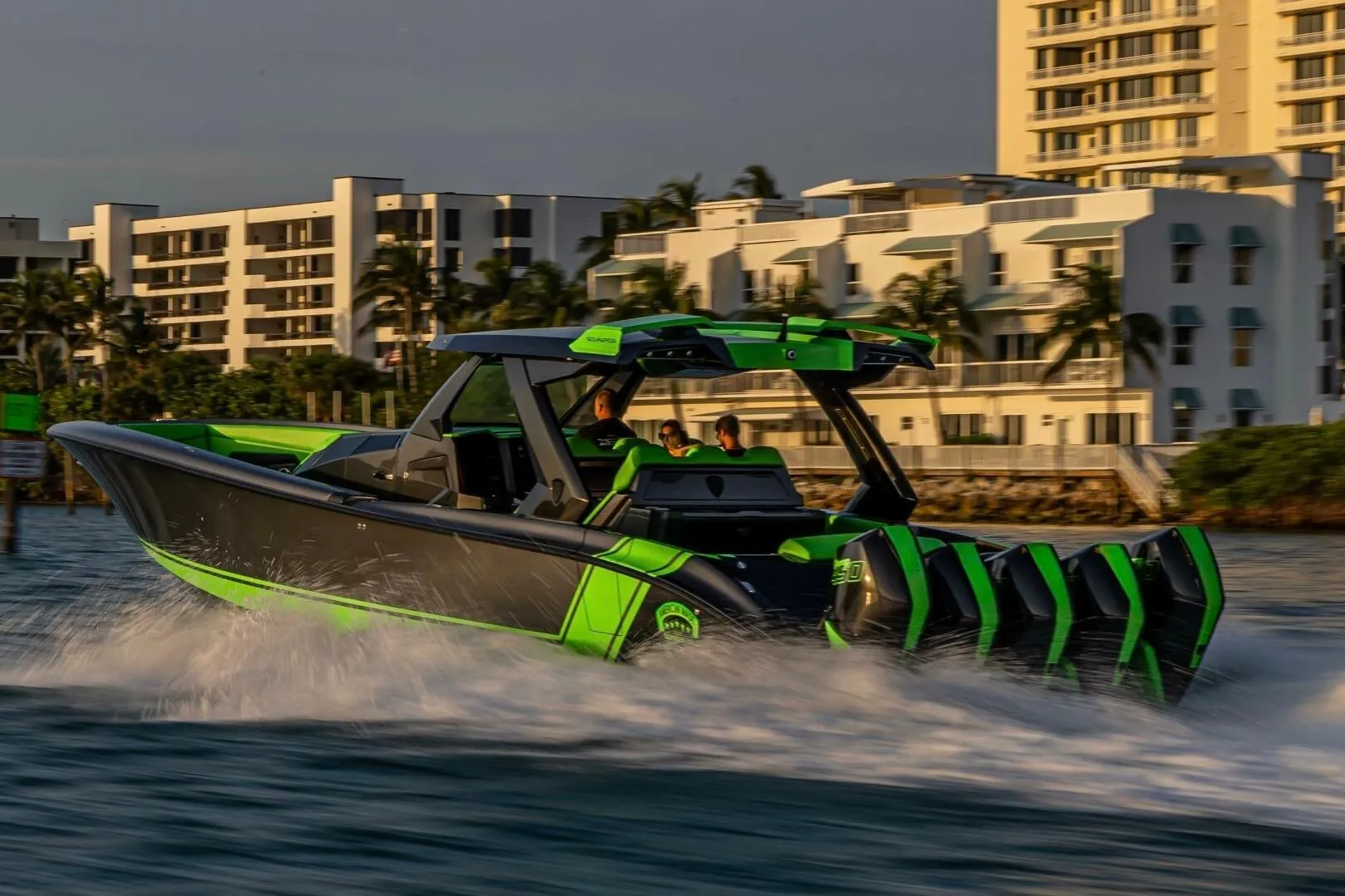 2023 Adrenaline 47 listing photograph showing a green-and-black performance boat underway beside waterfront buildings
